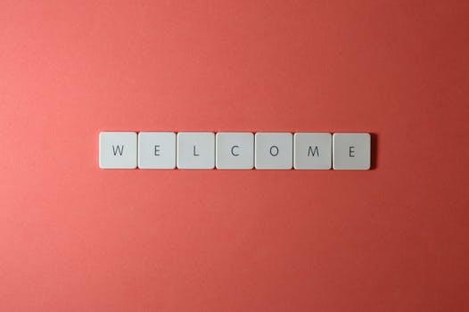 Flat lay of white tiles spelling 'WELCOME' on a red background