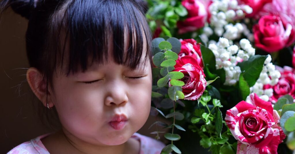 pexels photo 32501394 32501394 Adorable child with eyes closed near vibrant rose bouquet, expressing delight.
