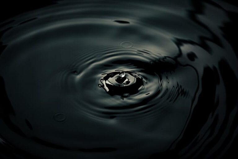 Intriguing shot of a water droplet creating ripples with dark reflections, showcasing smooth motion.