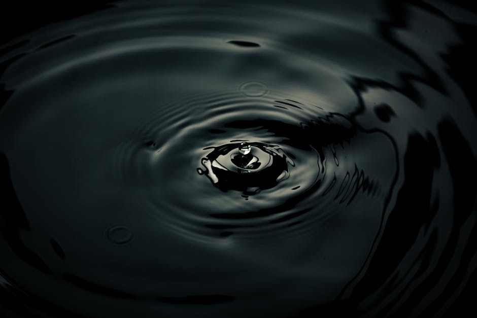Intriguing shot of a water droplet creating ripples with dark reflections, showcasing smooth motion.