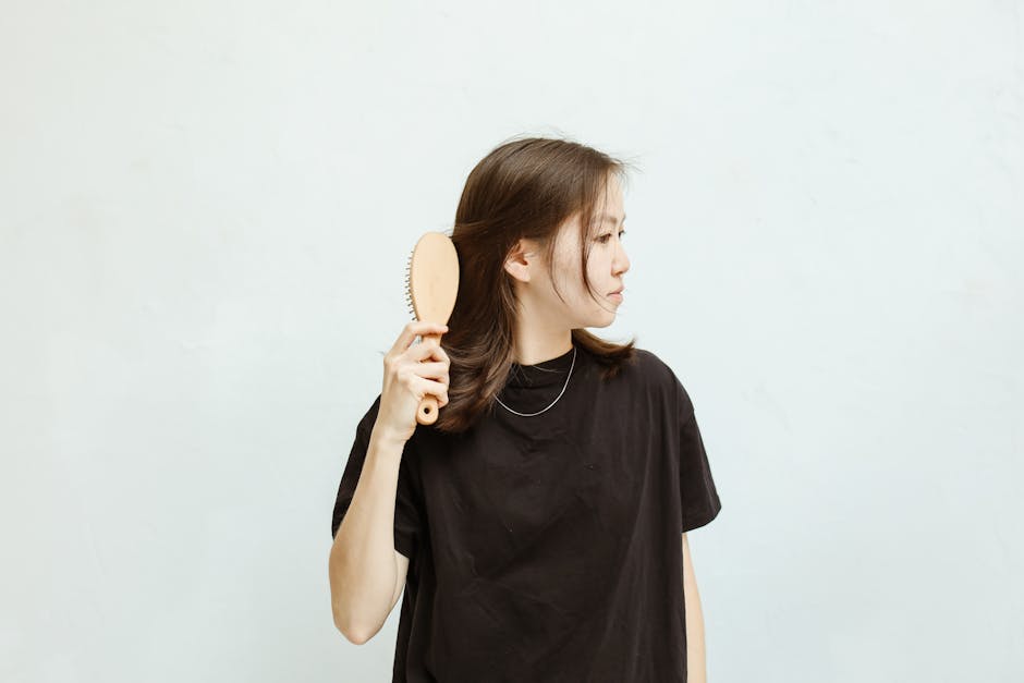 pexels photo 5468605 5468605 A young woman in a black shirt combs her hair against a white background.